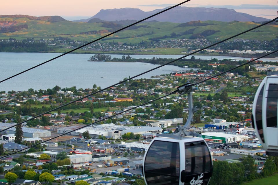 Une télécabine surplombe une ville, avec un lac et des montagnes en arrière-plan.