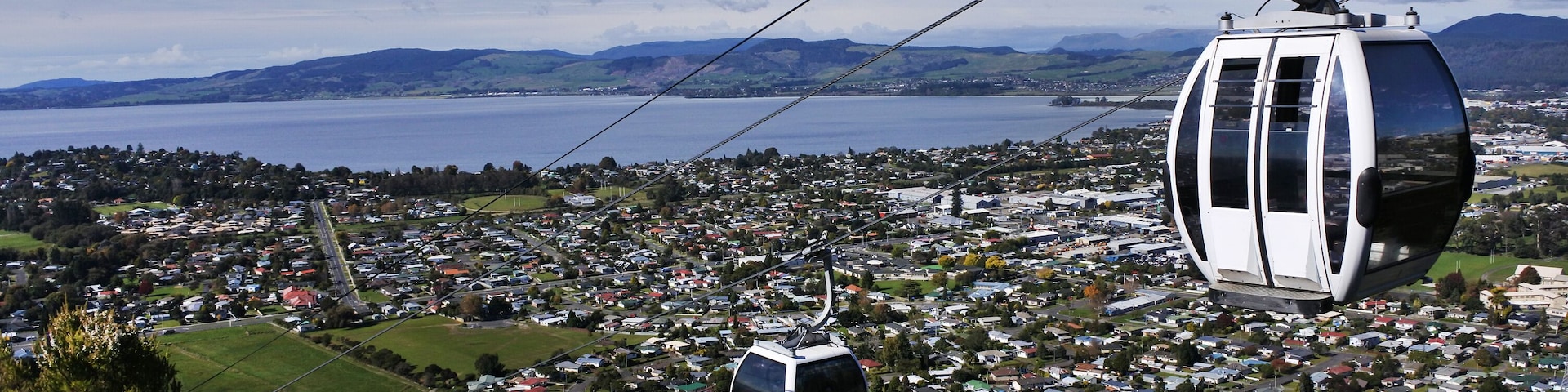 A cable car system over a town with a lake and mountains in the background.