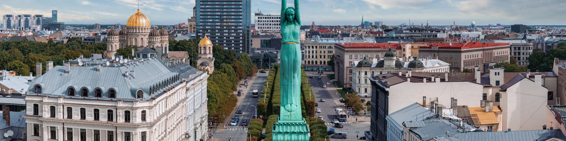 A cityscape with a prominent green statue, historic buildings, and a modern skyscraper.