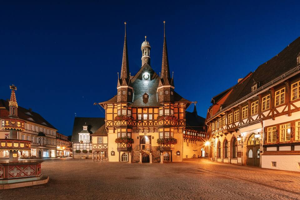 A historic town square with a prominent church featuring twin spires and a central fountain.