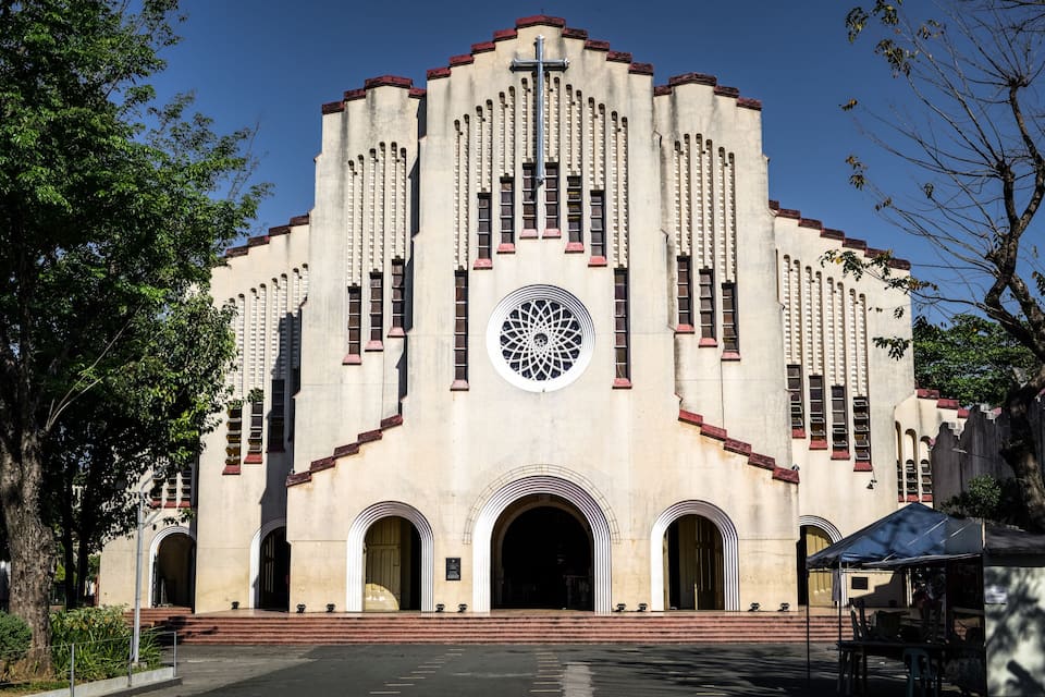 A large, historic building with a central circular window and multiple arched entrances.