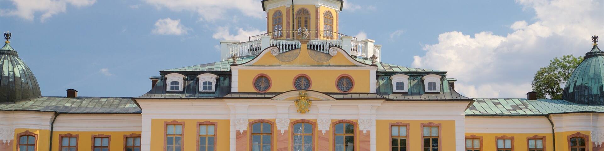 Un grand bâtiment jaune, doté d’un dôme central et de fenêtres en arc de cercle.
