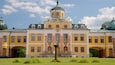 A large yellow building with a central dome and arched windows.