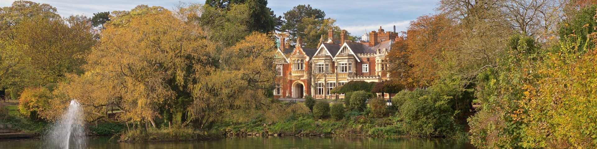 A historic house by a lake with a fountain.