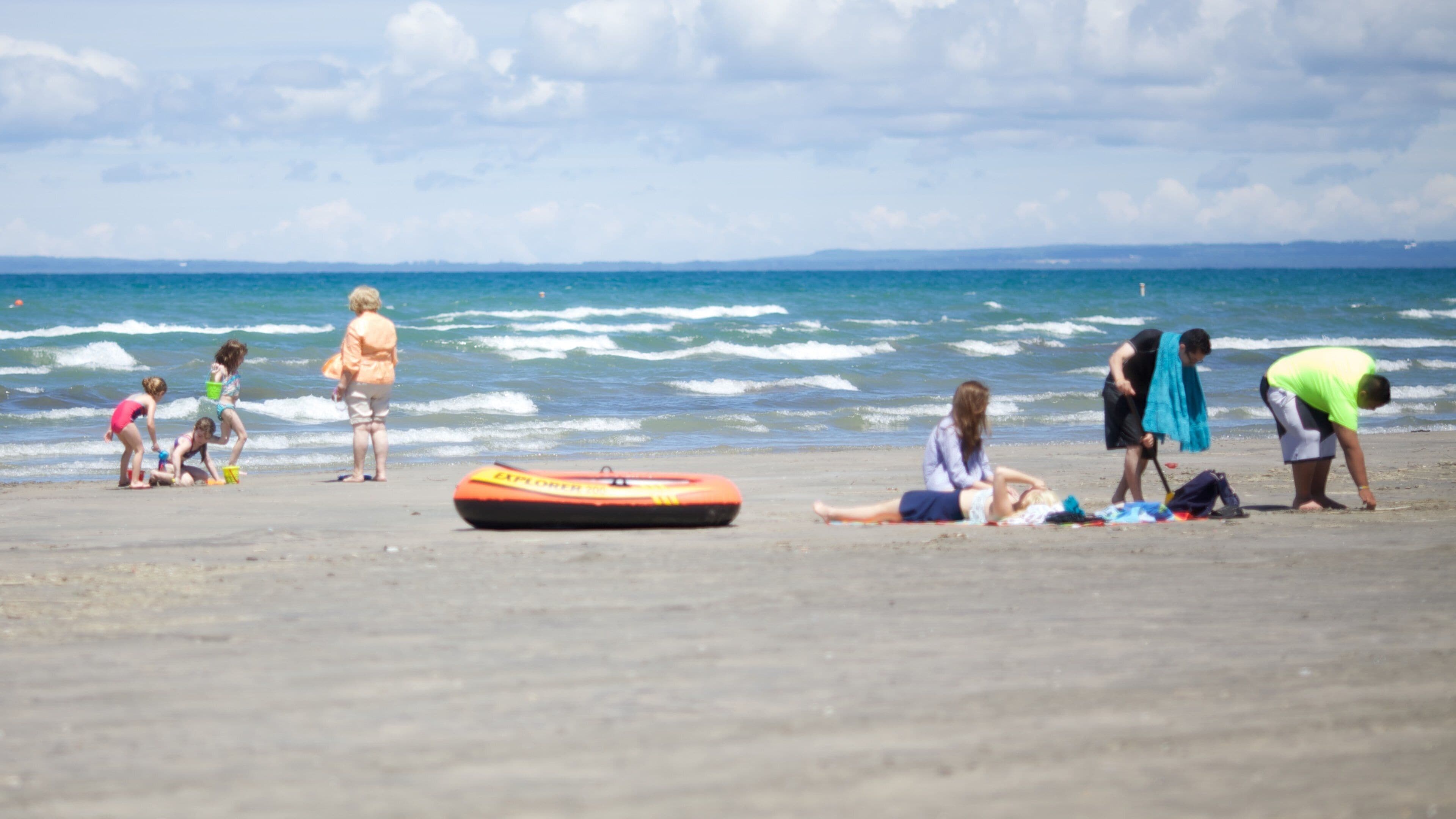 A beach with people playing and a lifeguard stand.