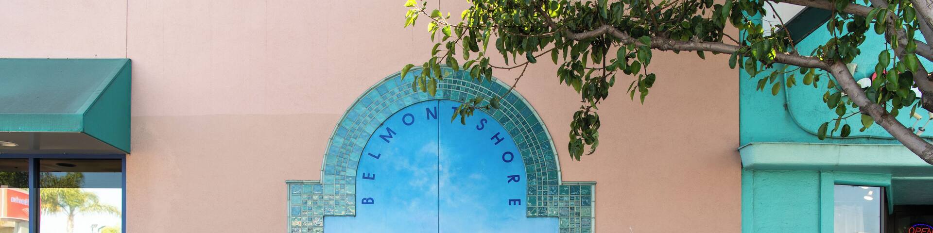 A turquoise storefront with a large mural of a sailboat on water. A bicycle is parked in front.
