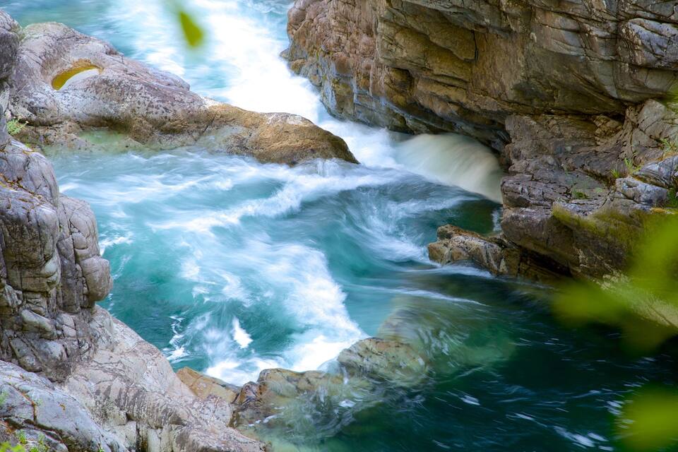 A river flowing through a rocky gorge with clear water and a waterfall.