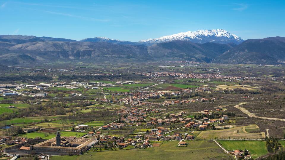 A town with a prominent church and a snow-capped mountain in the background.