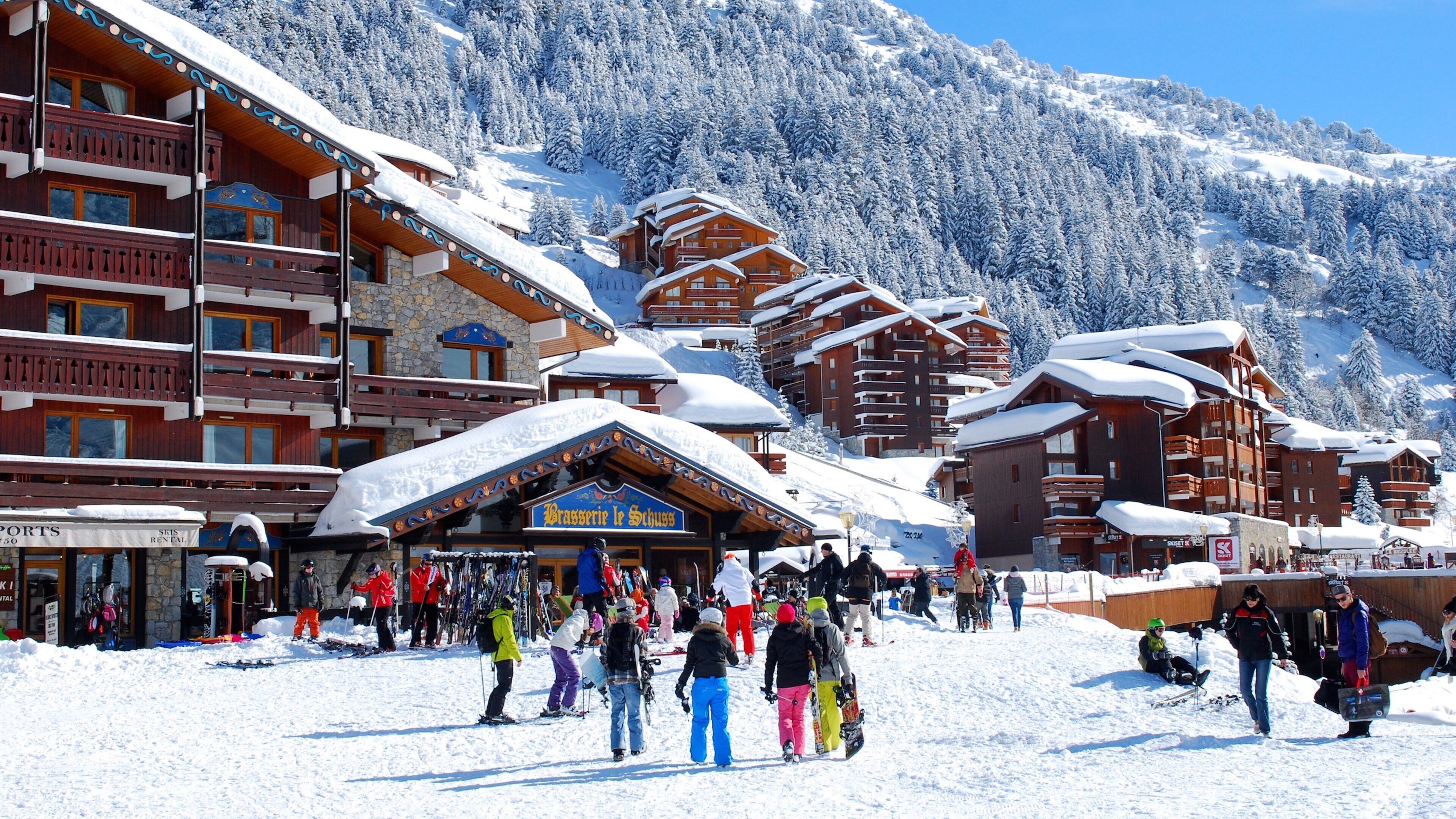A snow-covered ski resort with wooden buildings and a bustling crowd.