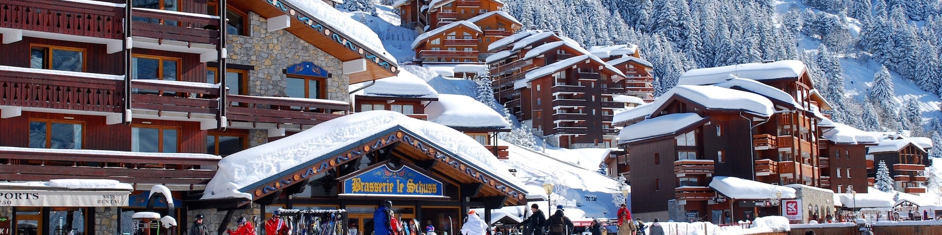 A snow-covered ski resort with wooden buildings and a bustling crowd.