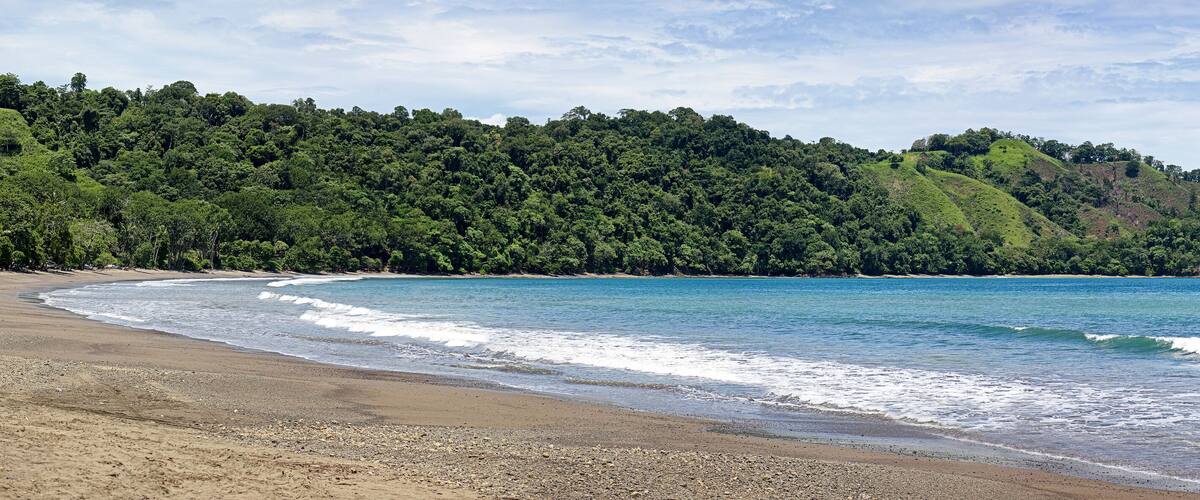 Pano of Playa Herradura, Beach, with turquoise water and some boats in Costa Rica