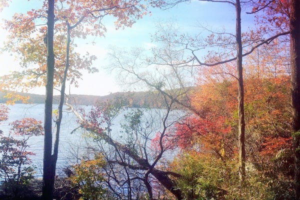 Un lac entouré d’arbres aux couleurs automnales et d’un paysage rocheux.