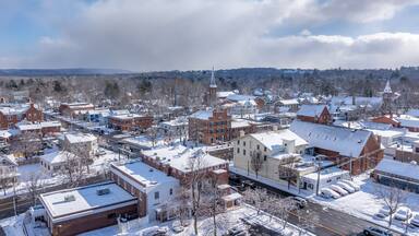 Pittsford, NY, USA - 02-01-2025: Winter afternoon aerial photo of the Village of Pittsford four corners with snow on the ground.
