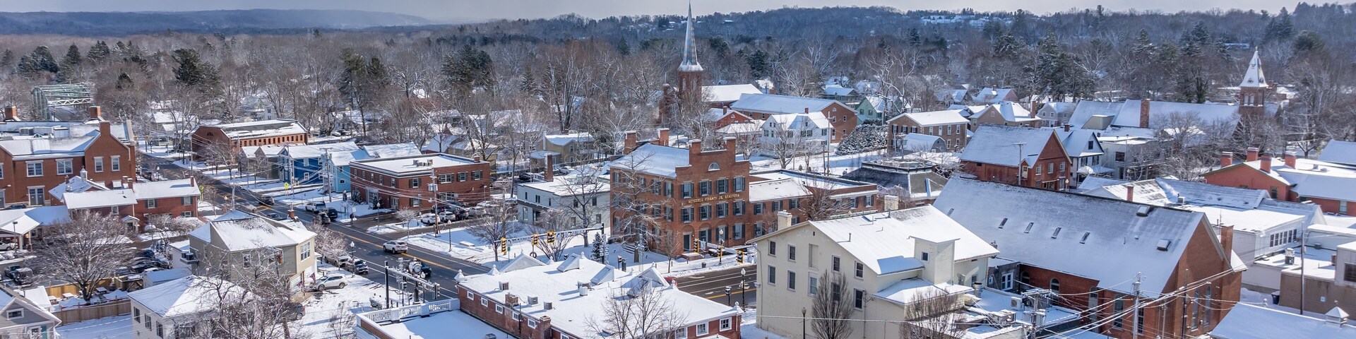 A snow-covered town with historic buildings and a church steeple.
