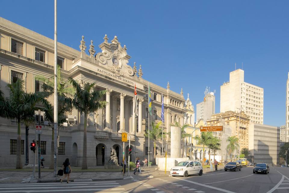 A historic building with ornate architecture, palm trees, and modern vehicles on the street.