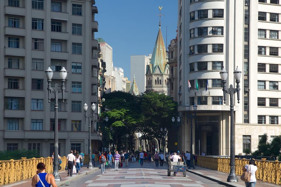 A busy urban street with tall buildings, a green-roofed church, and pedestrians.