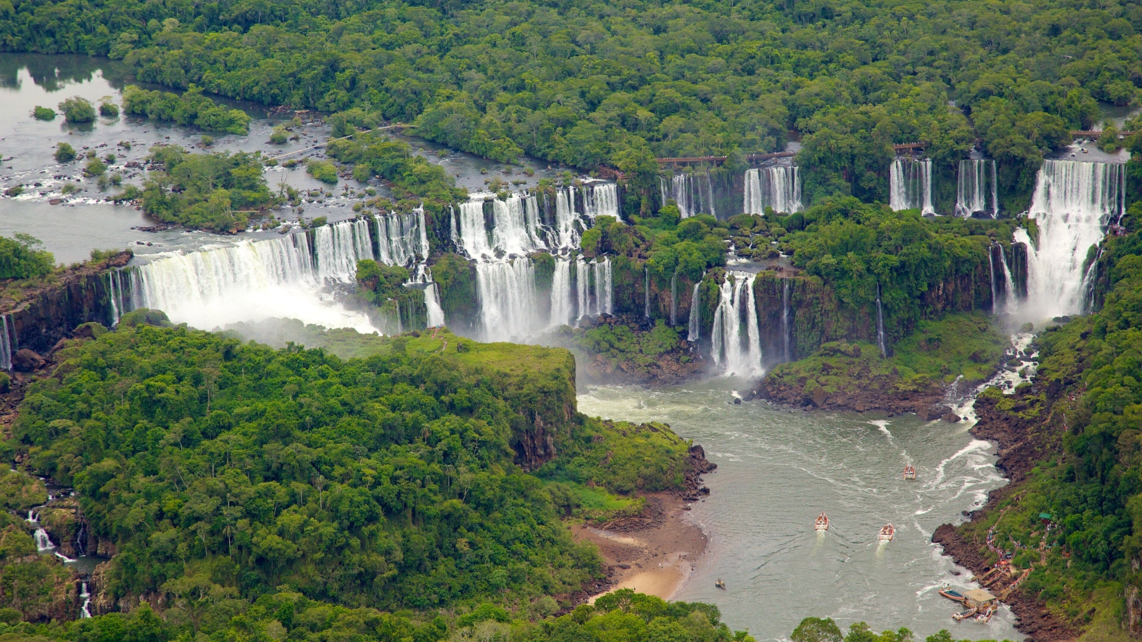 Una serie de cascadas que fluyen por un río rodeado de bosque denso.