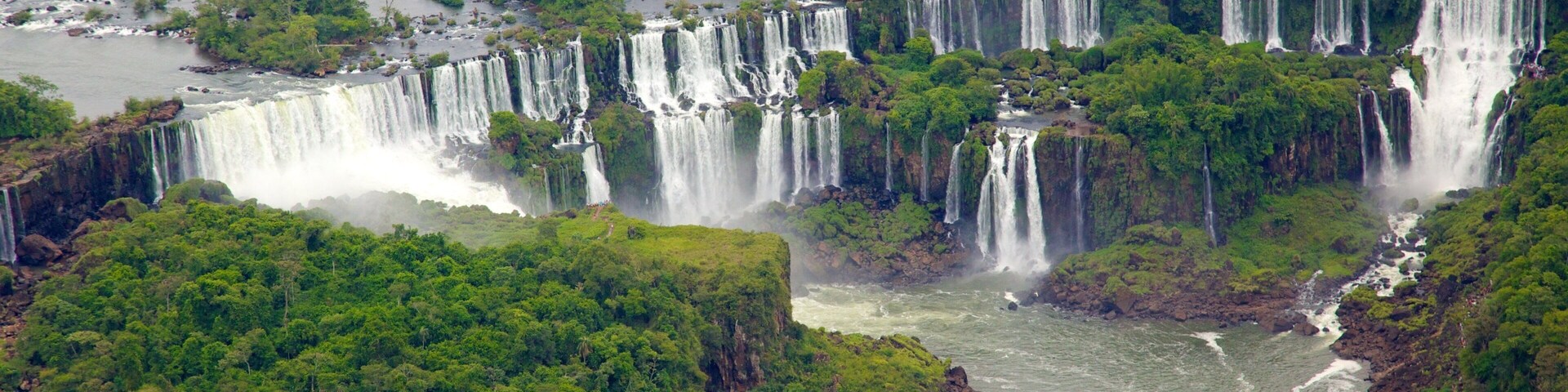 Una serie de cascadas que fluyen por un río rodeado de bosque denso.