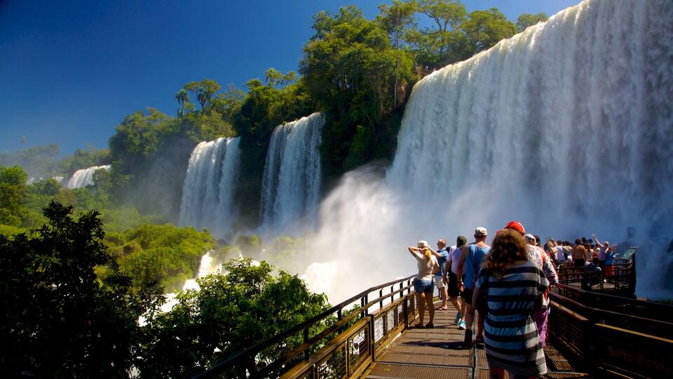A large waterfall with multiple tiers, surrounded by lush greenery and a viewing platform with people observing.