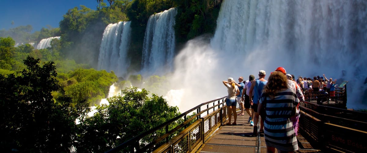 A large waterfall with multiple tiers, surrounded by lush greenery and a viewing platform with people observing.