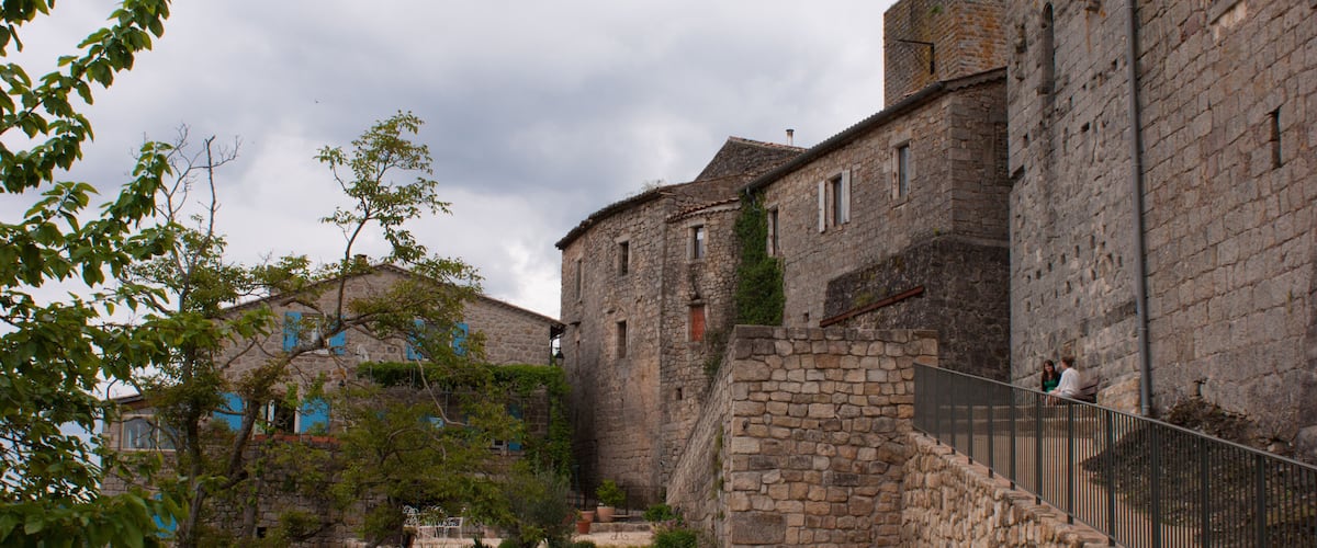 A historic stone building with a staircase and a fenced area.
