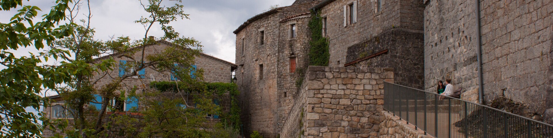 A historic stone building with a staircase and a fenced area.