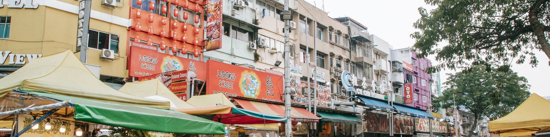 A bustling street market with food stalls and people shopping.