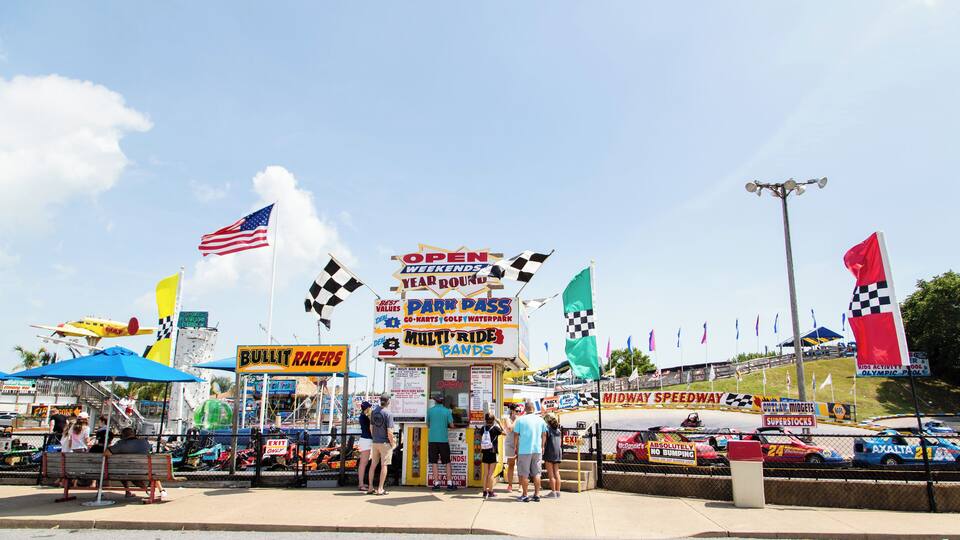 A racing event with flags, a pit stop, and a Midway Speedway sign.
