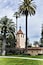 A church with a bell tower, surrounded by palm trees and a well-maintained lawn.