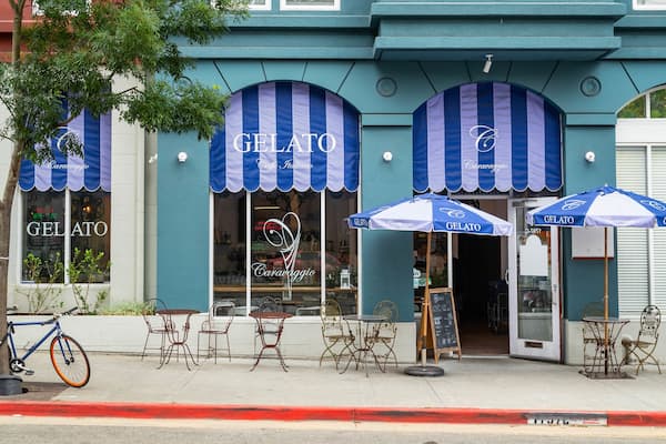 A gelato shop with blue and white striped awnings and outdoor seating.