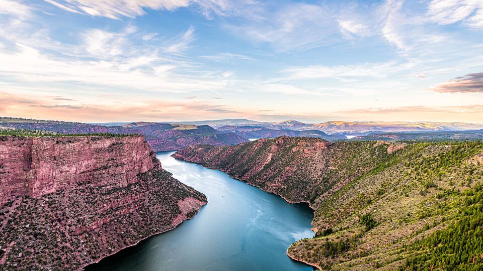 A canyon with a river, mountains, and a clear sky.
