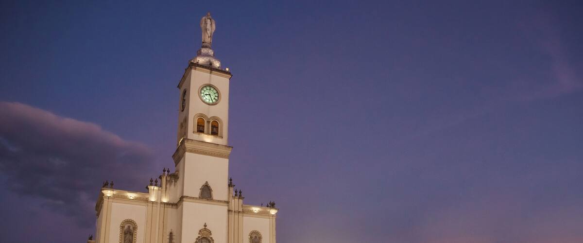 A tall white church with a clock tower against a twilight sky.