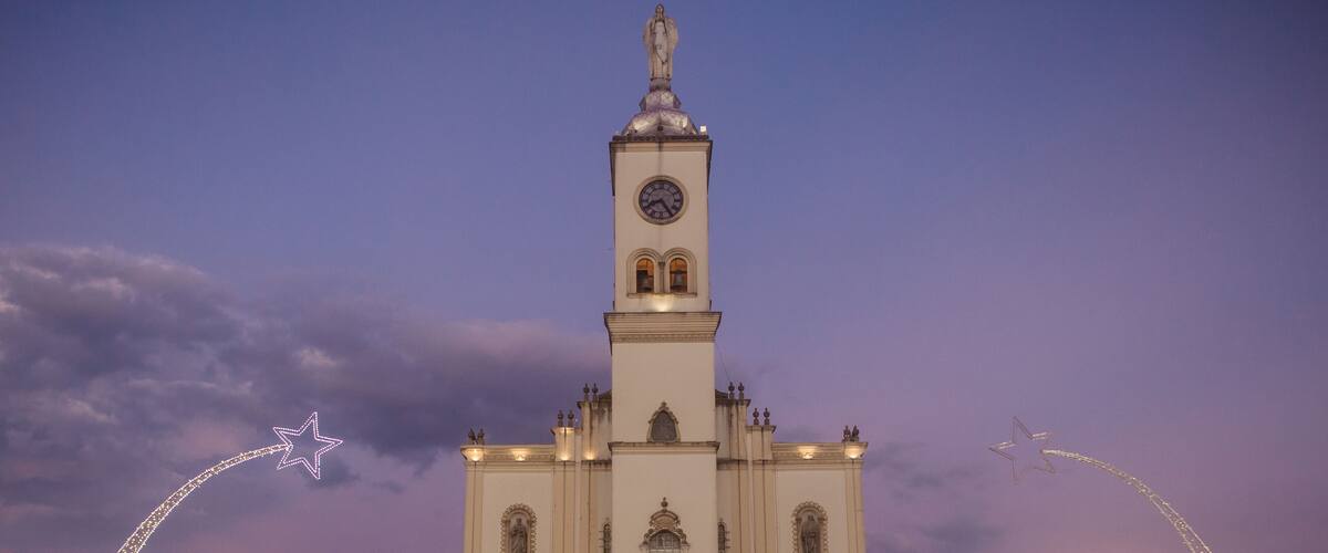 Een hoge witte kerk met een klokkentoren, tegen een schemerige lucht.