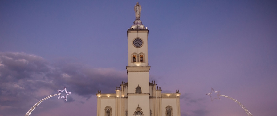 Een hoge witte kerk met een klokkentoren, tegen een schemerige lucht.