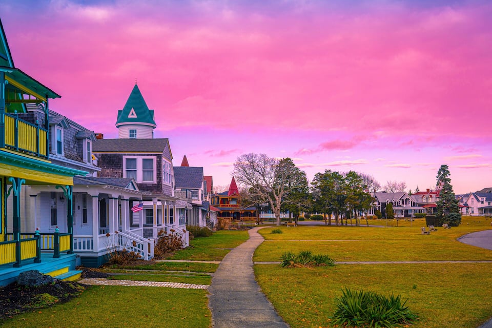 Una hilera de casas coloridas con una torre destacada, un césped y un camino sinuoso.