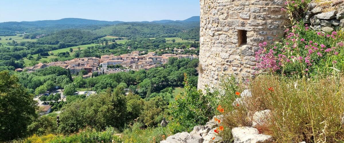 A stone tower overlooking a village surrounded by lush green hills.