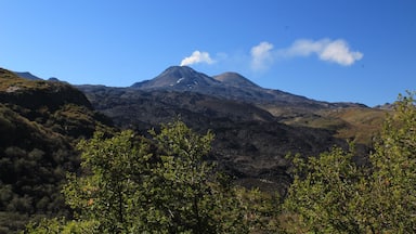 Una montaña con un pico prominente y una pequeña nube sobre él.