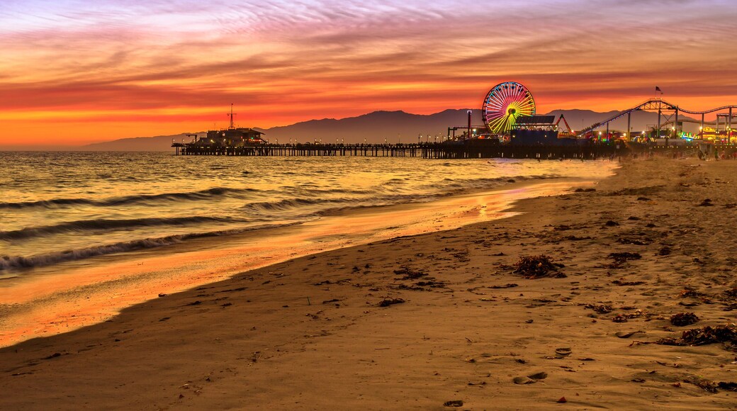 Santa Monica Historic Landmark, California, United States. Amazing landscape of iconic Santa Monica Pier at orange red sunset sky from beach on Paficif Ocean. Banner panorama background.