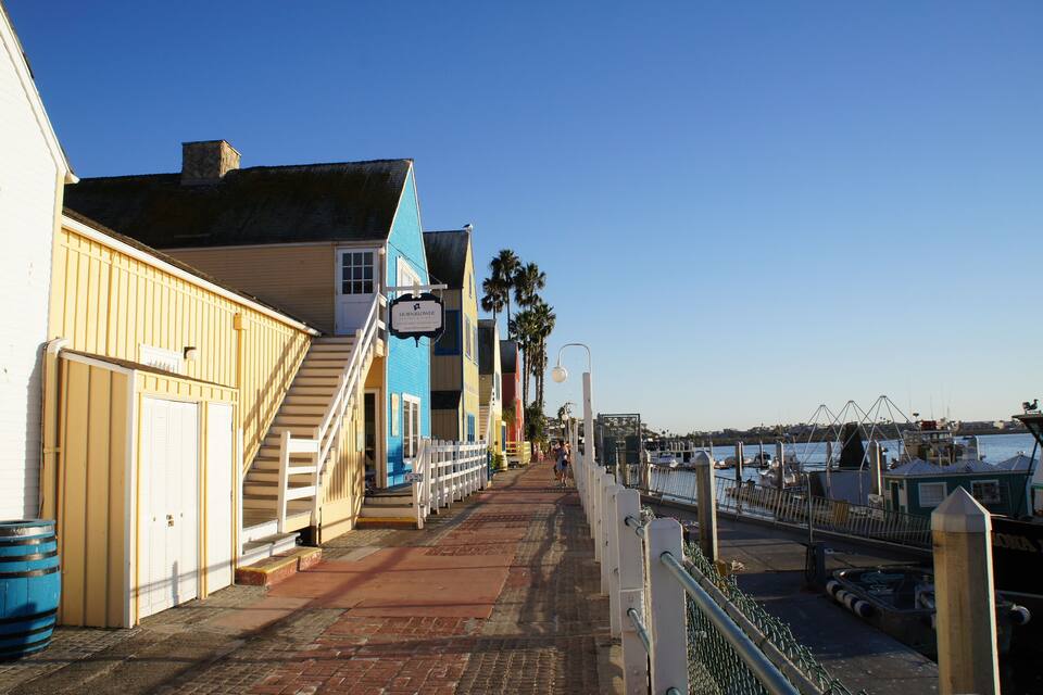 Un paseo marítimo con edificios, una escalera y un puerto deportivo.