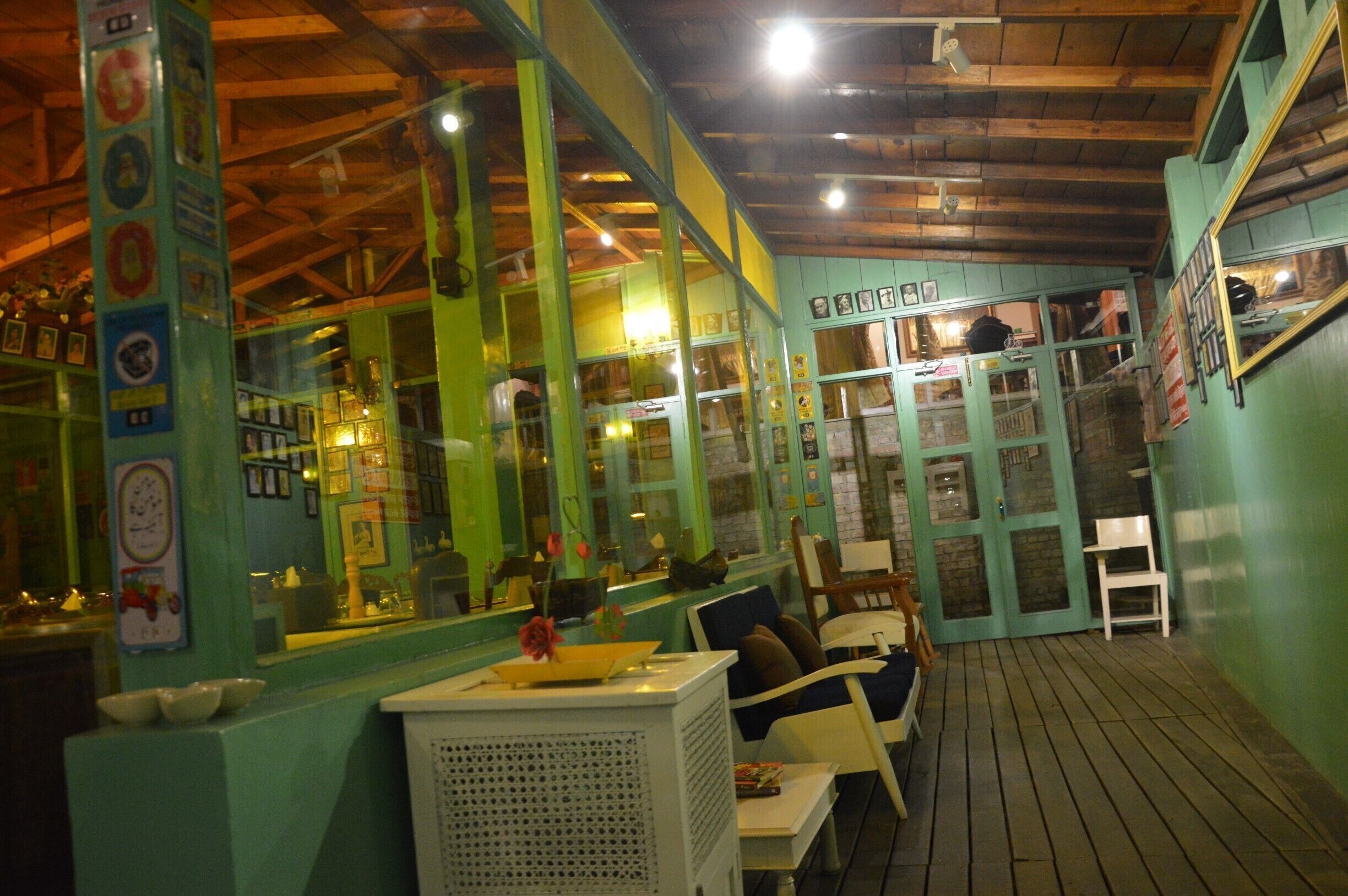 A restaurant interior with green walls, wooden ceiling, and a wooden floor.