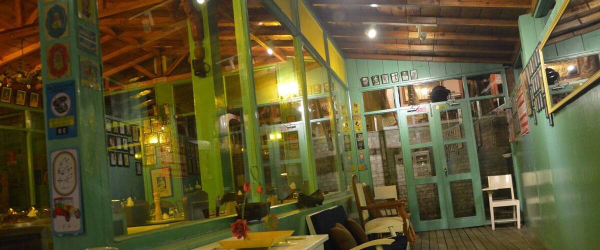 A restaurant interior with green walls, wooden ceiling, and a wooden floor.