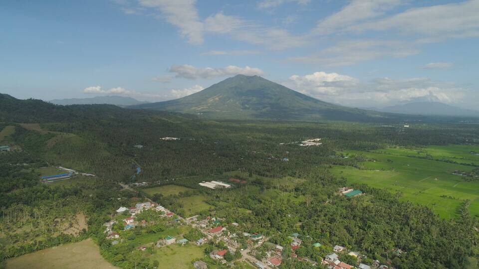 Aerial view of town in a mountain valley at the foot of the mountain Iriga. Luzon, Philippines. Mountainous tropical landscape.