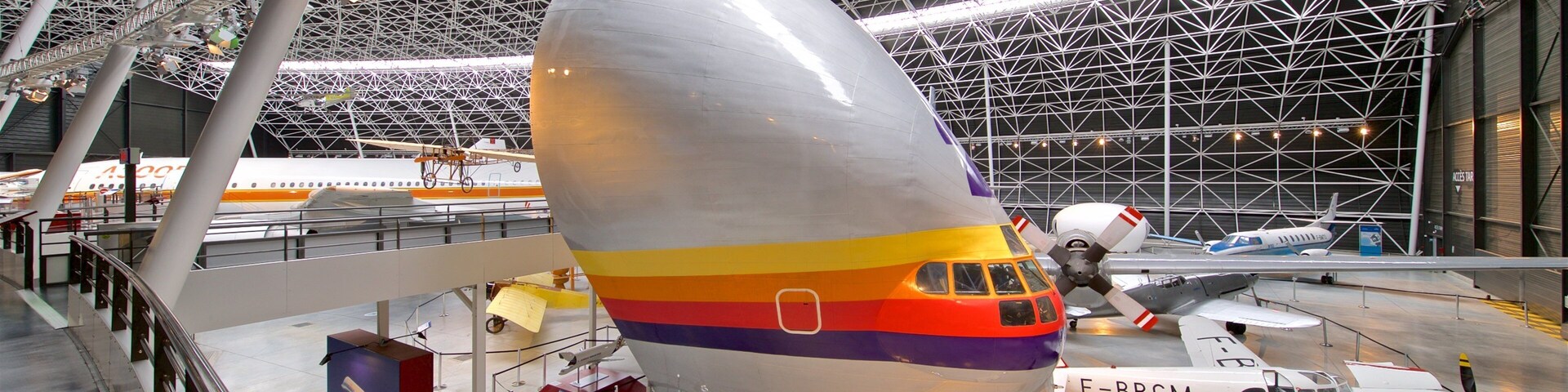 A large airplane with a rainbow stripe parked inside a hangar.