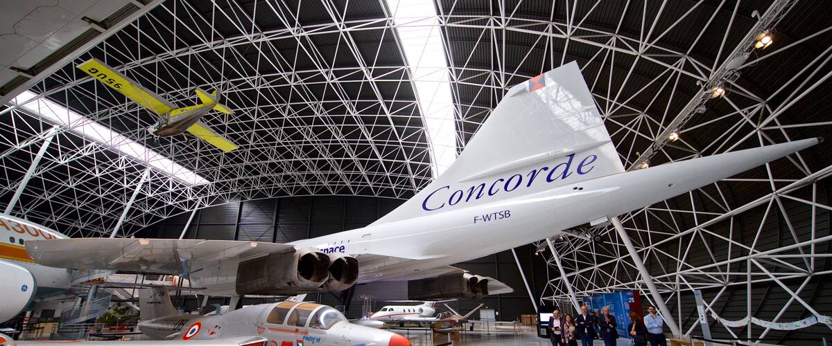 Concorde F-WTSB in a museum with a netted ceiling and other aircraft.