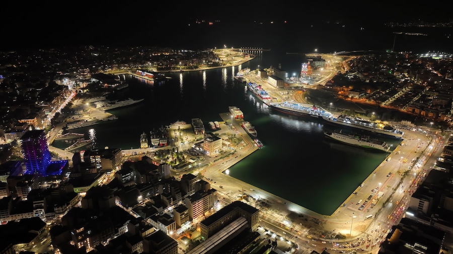 Aerial drone night shot of illuminated tower of Piraeus and port of Piraeus during Christmas period, Attica, Greece