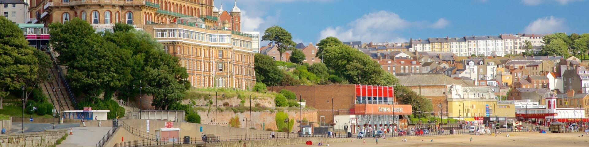 A coastal town with a prominent historic building, a sandy beach, and a promenade.