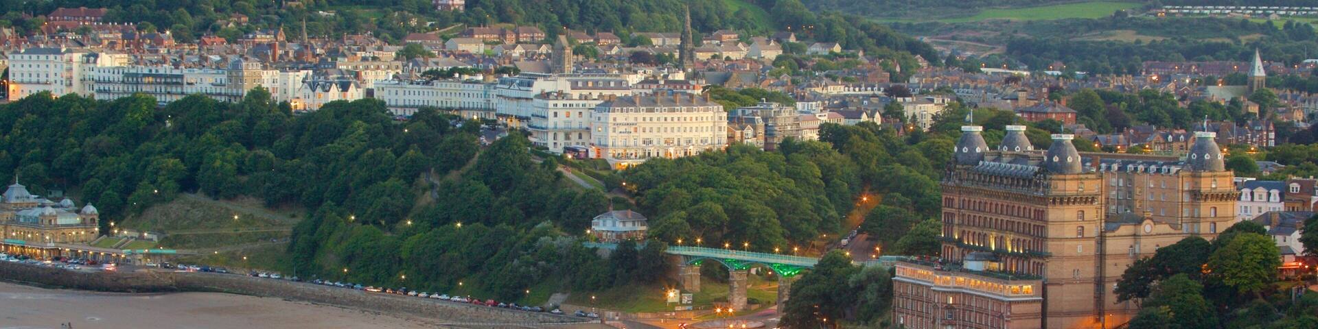 Un paisaje urbano costero con playa, edificios históricos y un puente verde.
