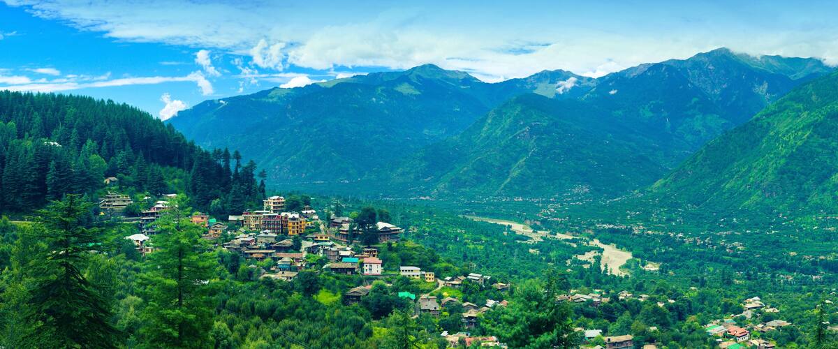 A mountainous village nestled in a valley with dense forests and a river.