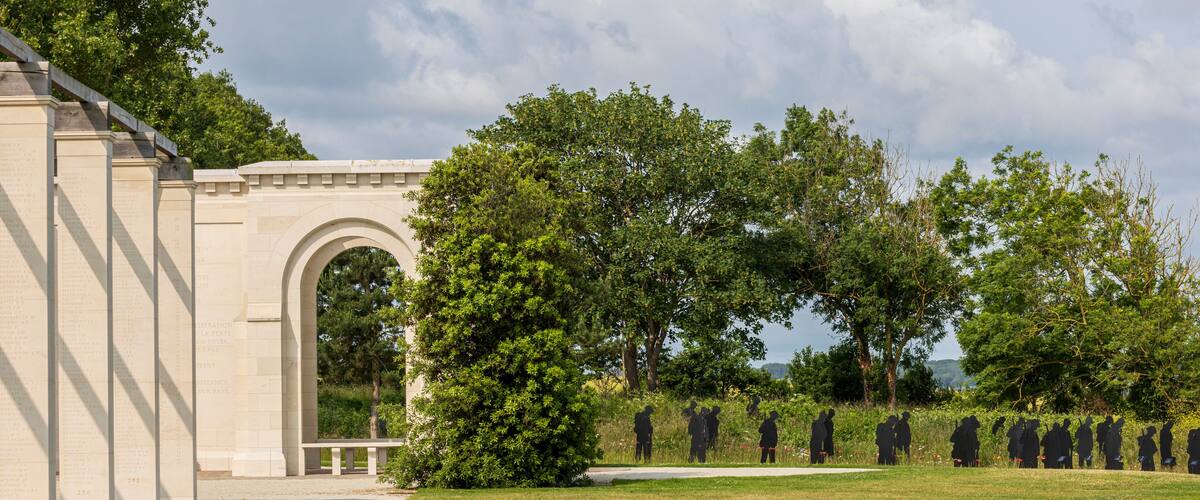 A memorial with an arched entrance, a pathway, and rows of black silhouettes.