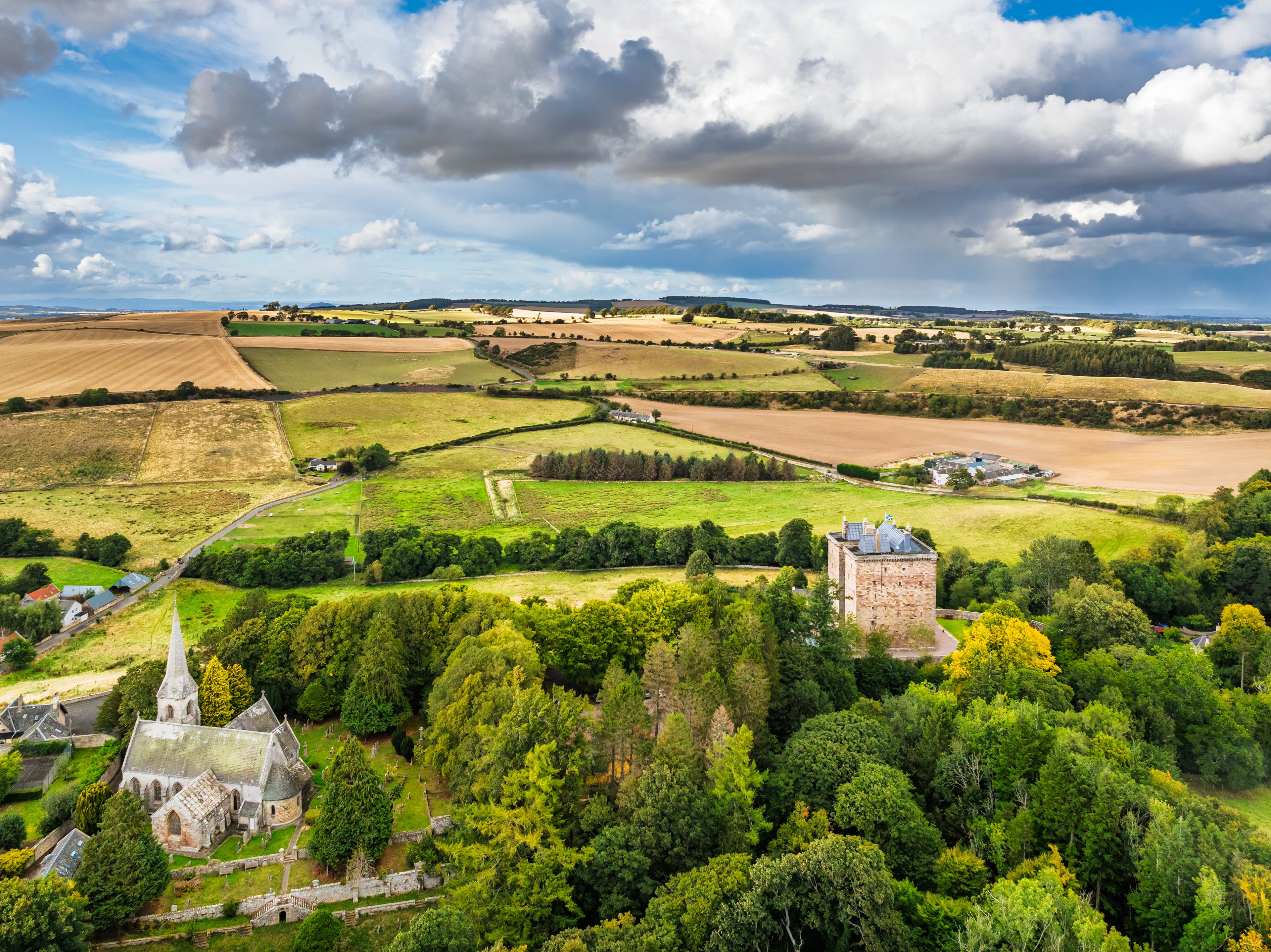 A rural landscape with fields, a church, and a castle.